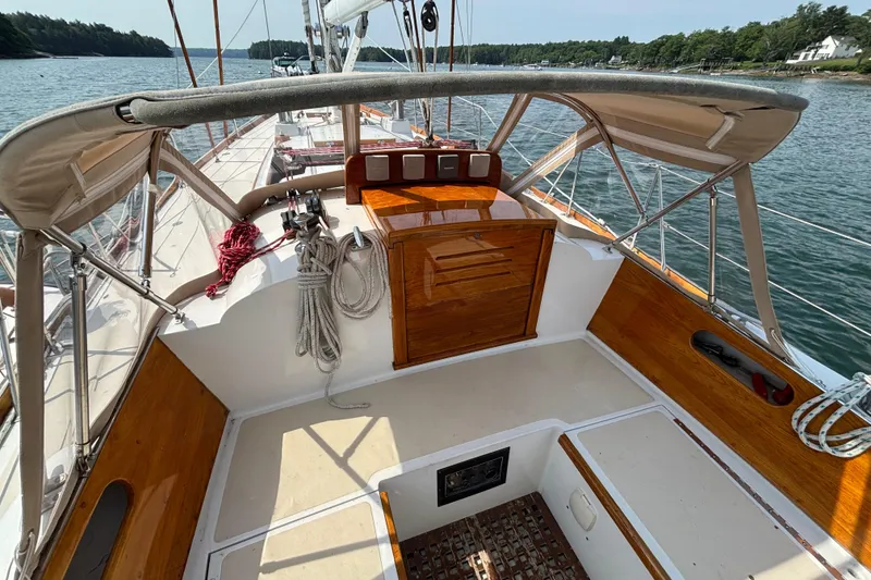 Slide: The Image of 1974 Hinckley Bermuda 40 MKIII sailboat cockpit with wooden accents, docked on calm water. - 15