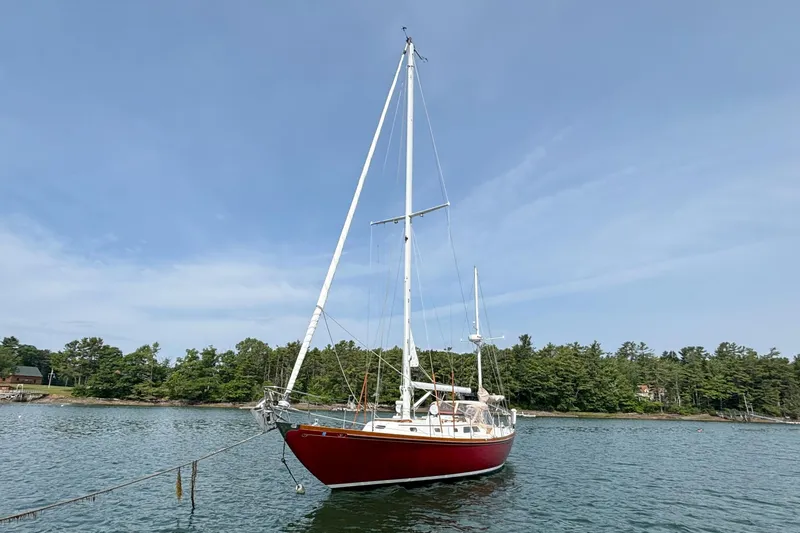 Slide: The Image of 1974 Hinckley Bermuda 40 MKIII sailboat anchored on calm water with forested shoreline. - 3