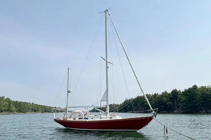 Slide: The Image of 1974 Hinckley Bermuda 40 MKIII sailboat anchored on calm water with forested shoreline. - 1