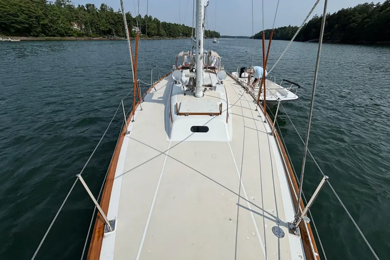 Slide: The Image of 1974 Hinckley Bermuda 40 MKIII sailboat on calm water, surrounded by lush greenery. - 9