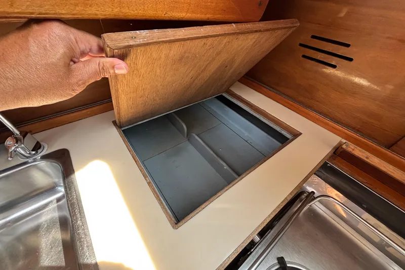 Slide: The Image of 1974 Hinckley Bermuda 40 MKIII galley with wooden storage compartment and stainless steel sink. - 33