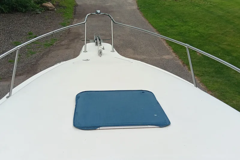 Slide: The Image of 1989 Searay 250 Sundancer boat deck with blue hatch cover, parked on a gravel path. - 14