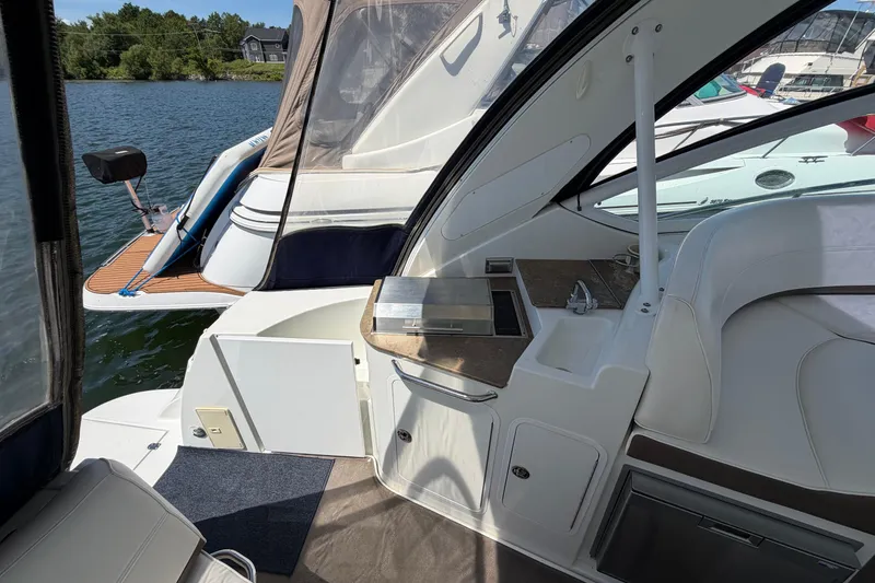 Slide: The Image of 2009 Cruisers Yachts 360 Express interior with kitchenette and seating, docked by the water. - 15