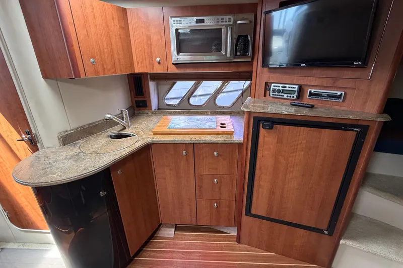 Slide: The Image of 2009 Cruisers Yachts 360 Express kitchen with wood cabinetry, microwave, and compact fridge. - 37