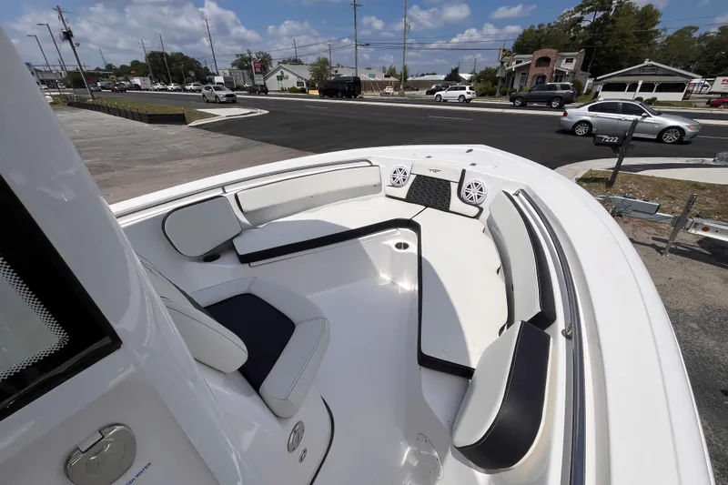 Slide: The Image of 2026 Tidewater 210 CC Adventure boat interior with cushioned seating and speakers, parked near a road. - 10
