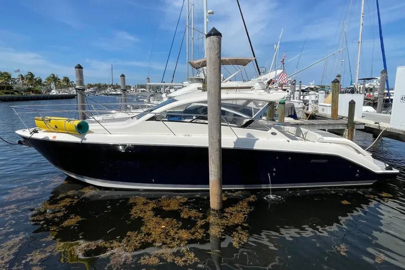 Slide: The Image of 2014 Pursuit SC 365i Sport Coupe docked at marina, clear blue sky background. - 2