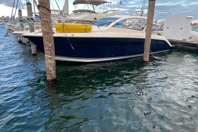 Slide: The Image of 2014 Pursuit SC 365i Sport Coupe docked at marina, blue hull, sleek design. - 9