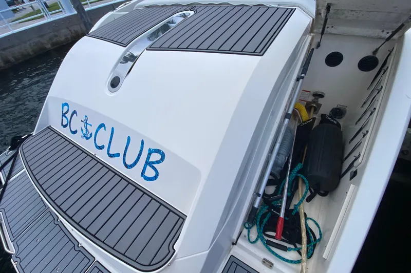 Slide: The Image of 2014 Pursuit SC 365i Sport Coupe boat with "BC Club" logo, docked with storage compartment open. - 24