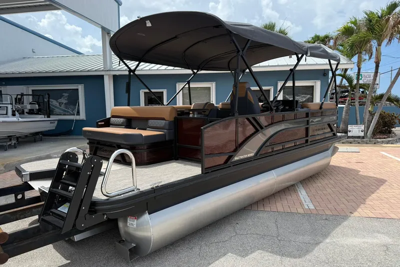 Slide: The Image of 2026 Bennington 21 SLJ pontoon boat with canopy, parked outdoors near a blue building. - 4