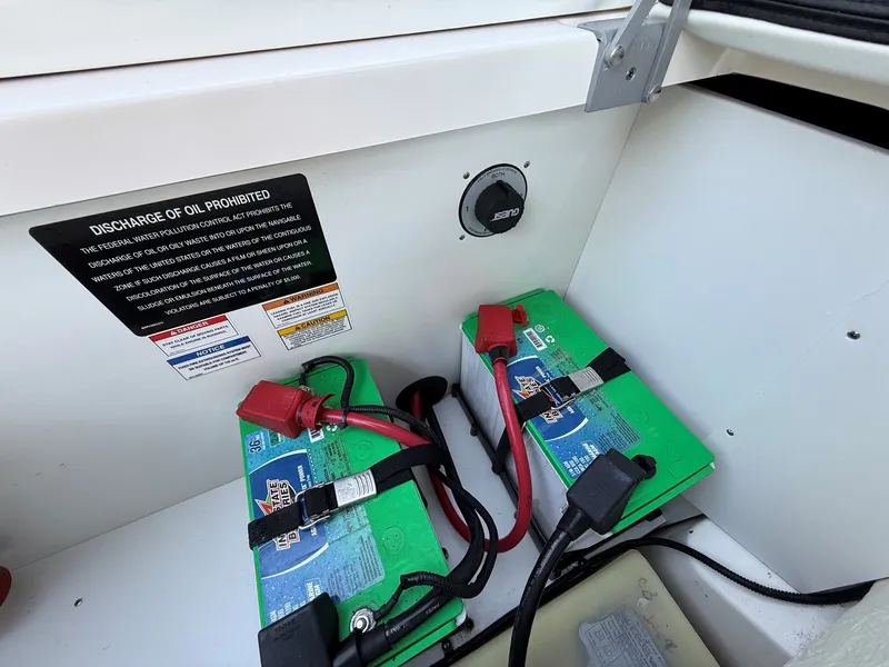 Slide: The Image of Battery compartment with two green batteries and cables in a Sea Ray SDX 290 boat. - 29