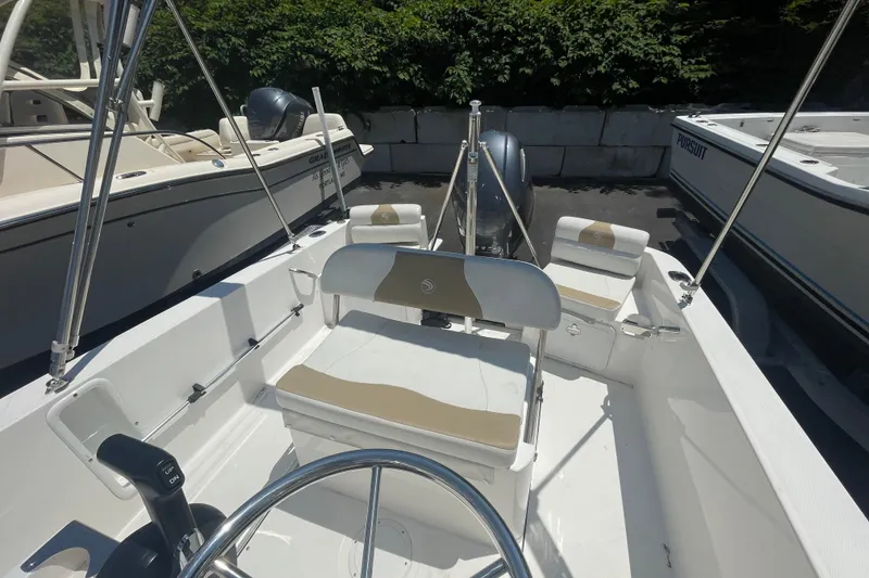 Slide: The Image of 2021 Edgewater 170CC boat interior with seating and steering wheel, docked alongside other boats. - 7