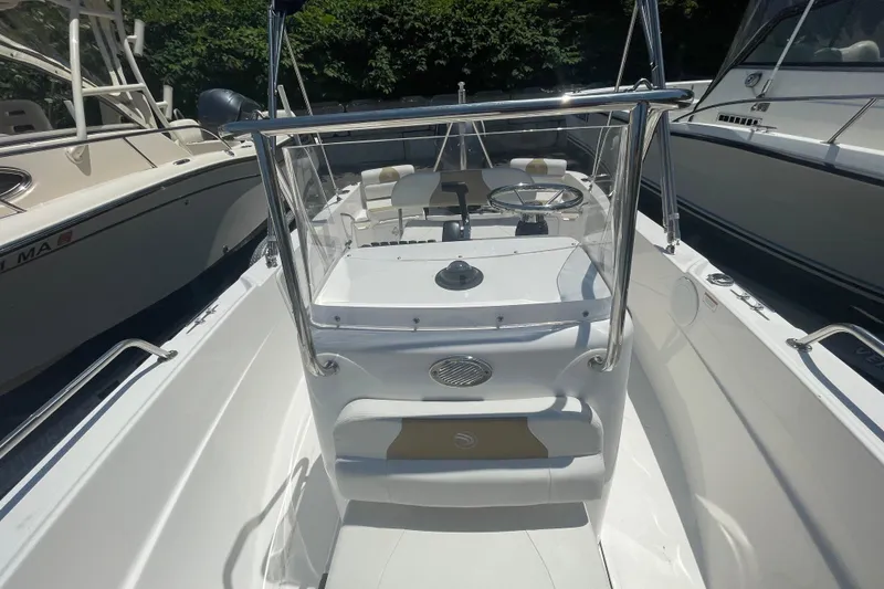 Slide: The Image of 2021 Edgewater 170CC boat interior with steering console and seating, docked among other boats. - 10