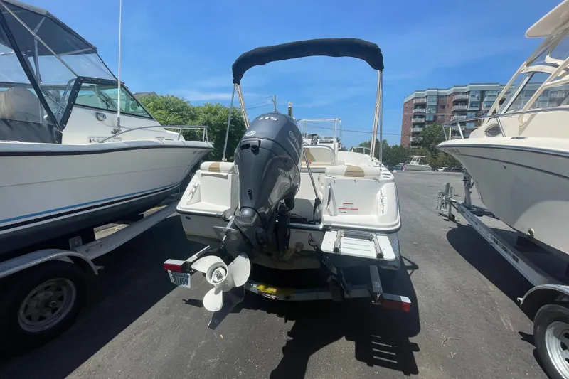 Slide: The Image of 2021 Edgewater 170CC boat with outboard motor, parked on a trailer in a marina. - 12