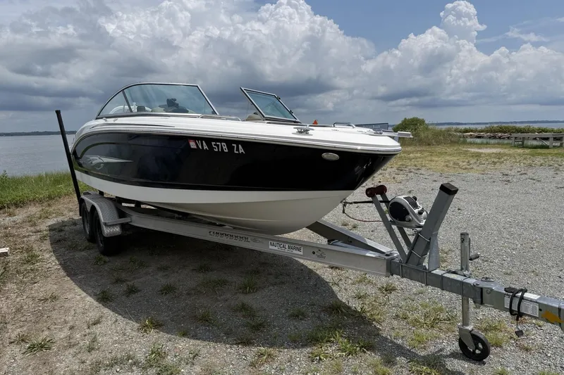 Slide: The Image of 2018 Chaparral 21 H2O Ski & Fish OB boat on trailer by a lake under cloudy sky. - 2