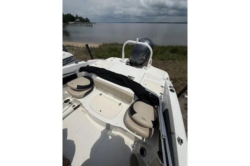 Slide: The Image of 2018 Chaparral 21 H2O Ski & Fish OB boat interior with seating, near a calm lake. - 10