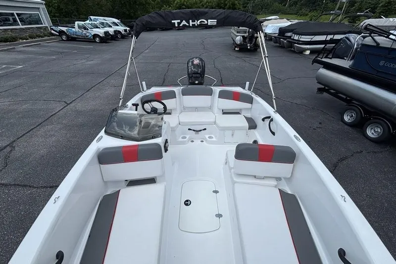 Slide: The Image of 2024 Tahoe T18 boat with seating, steering wheel, and canopy in a parking lot. - 34