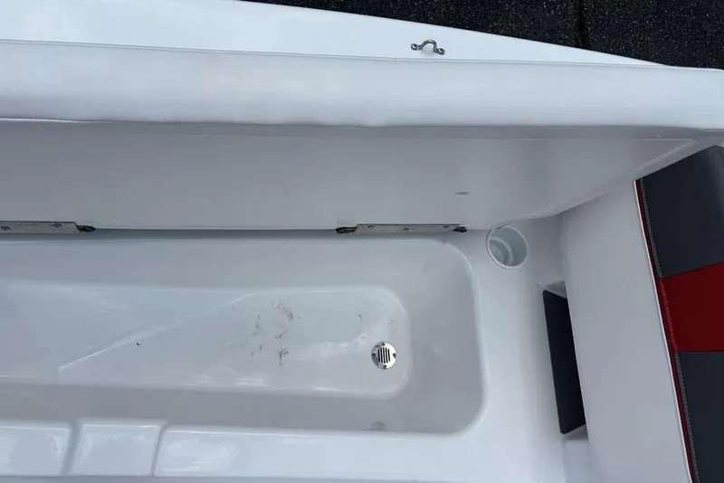 Slide: The Image of 2024 Tahoe T18 boat storage compartment with drain plug and white interior. - 18