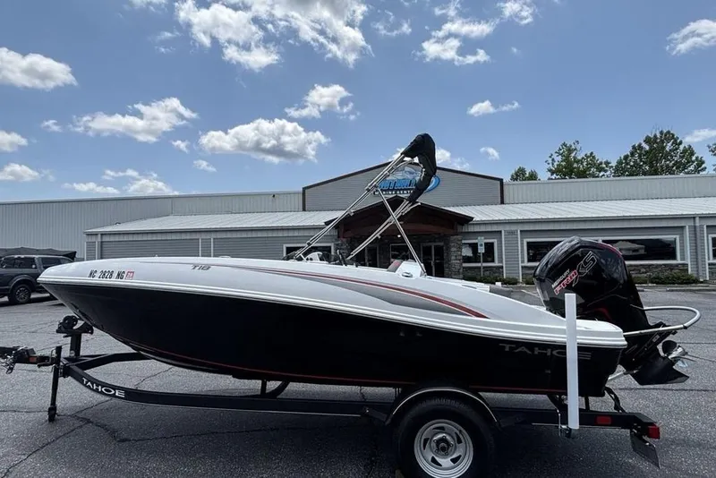 The Image of 2024 Tahoe T18 boat on trailer, parked outside a dealership under a partly cloudy sky. - 1