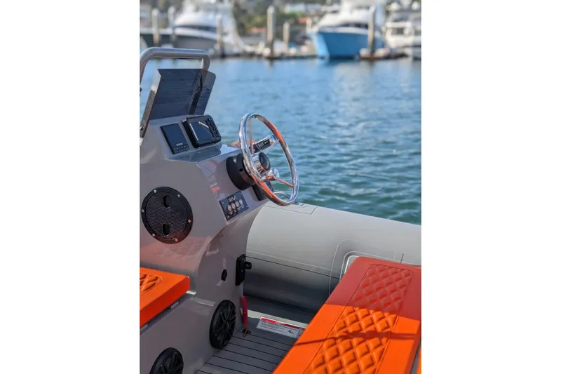 Slide: The Image of 2027 Tide Craft Nantucket 12 boat interior with orange seating, steering wheel, and control panel. - 5