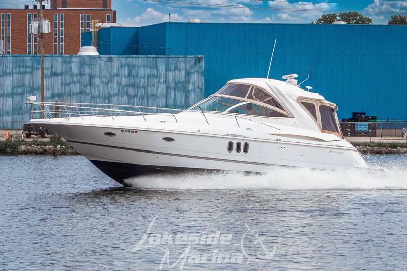 Slide: The Image of A 2006 Cruisers Yachts 420 Express speeds along a river against an urban backdrop. - 1