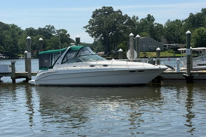 The Image of 2001 Sea Ray 340 Sundancer docked at a marina, surrounded by calm water and trees. - 0