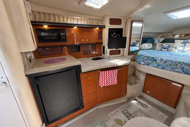 Slide: The Image of Interior of 2001 Sea Ray 340 Sundancer yacht with kitchenette and cozy sleeping area. - 17