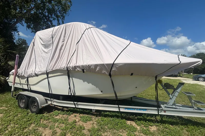 Slide: The Image of 2016 Sea Fox 249 Avenger boat covered on trailer, parked on grass under blue sky. - 89