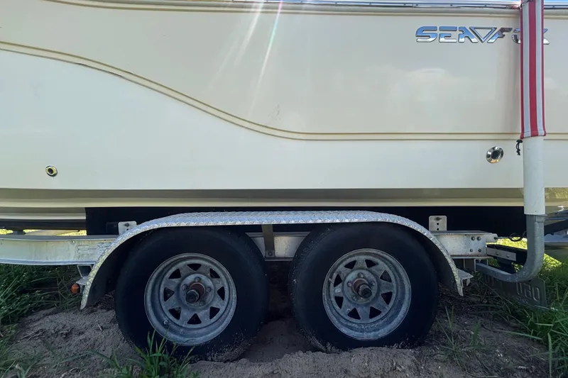 Slide: The Image of Trailer with 2016 Sea Fox 249 Avenger boat, parked on grassy terrain. - 84