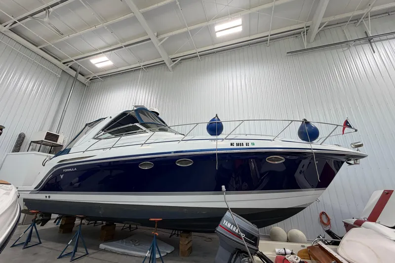 The Image of 2004 Formula 34 Performance Cruiser in storage, blue and white hull, indoor facility. - 0