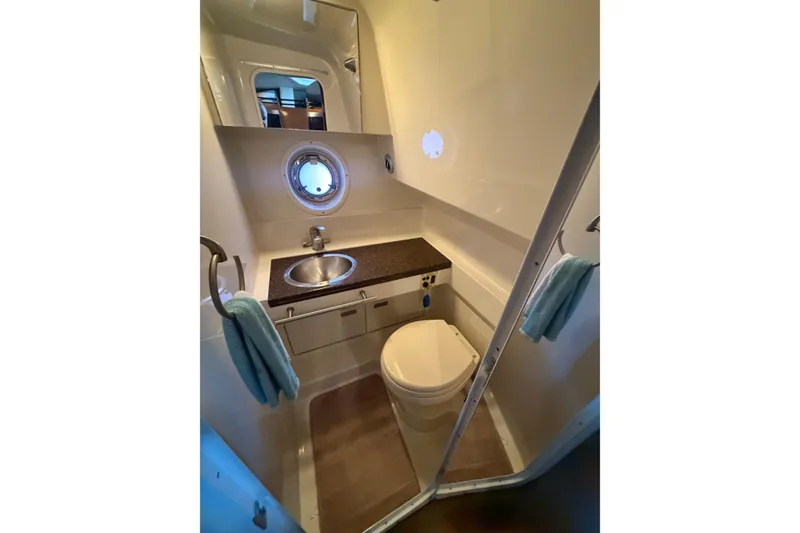 Slide: The Image of 2012 Sea Ray Sundancer 310 bathroom with sink, toilet, and porthole window. - 29