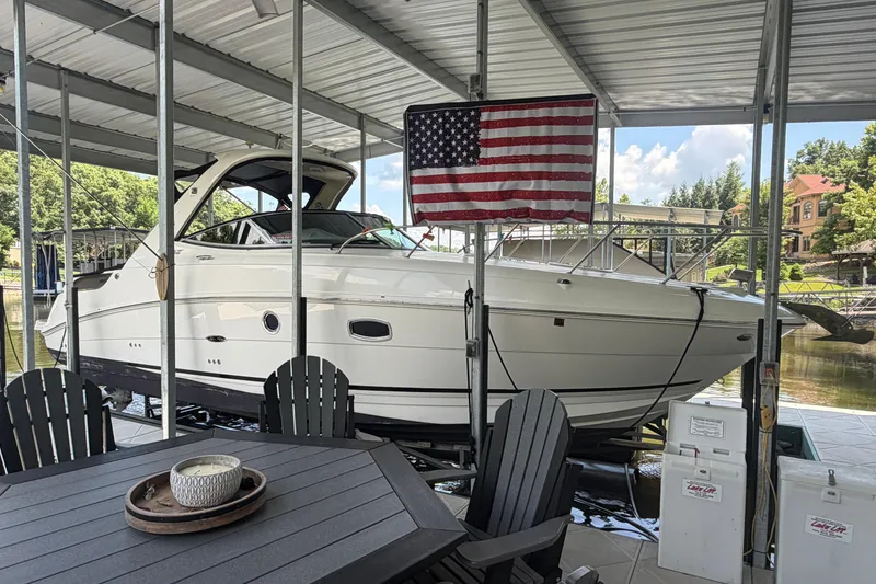 Slide: The Image of 2012 Sea Ray Sundancer 310 docked under a covered marina with American flag. - 2