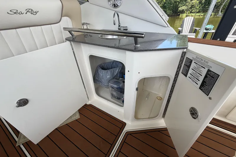 Slide: The Image of 2012 Sea Ray Sundancer 310 boat kitchenette with open storage cabinets and sink. - 11