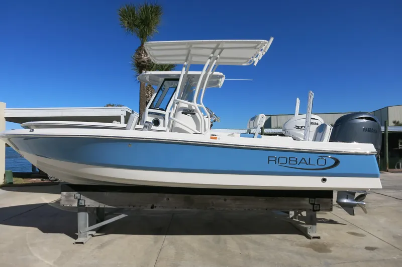 The Image of 2026 Robalo 206 Cayman boat with blue hull, docked outdoors under clear sky. - 0