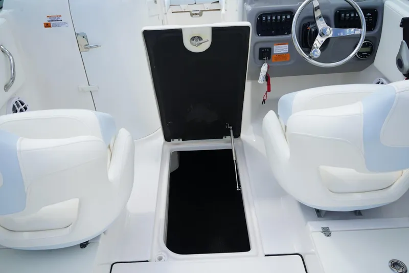 Slide: The Image of 2025 Robalo R207 Dual Console interior with open storage compartment and steering wheel. - 10