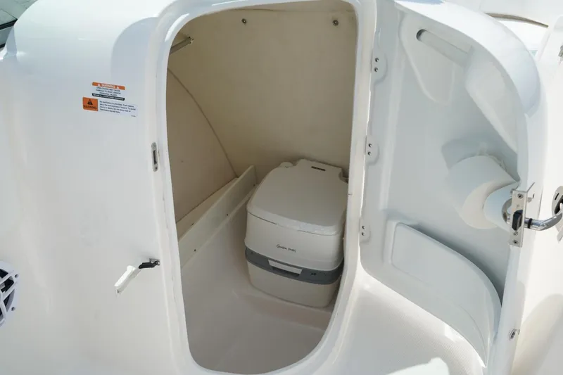 Slide: The Image of 2025 Robalo R207 Dual Console boat interior with compact marine toilet. - 7