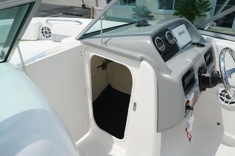 Slide: The Image of 2025 Robalo R207 Dual Console boat interior with steering wheel and storage compartment. - 9