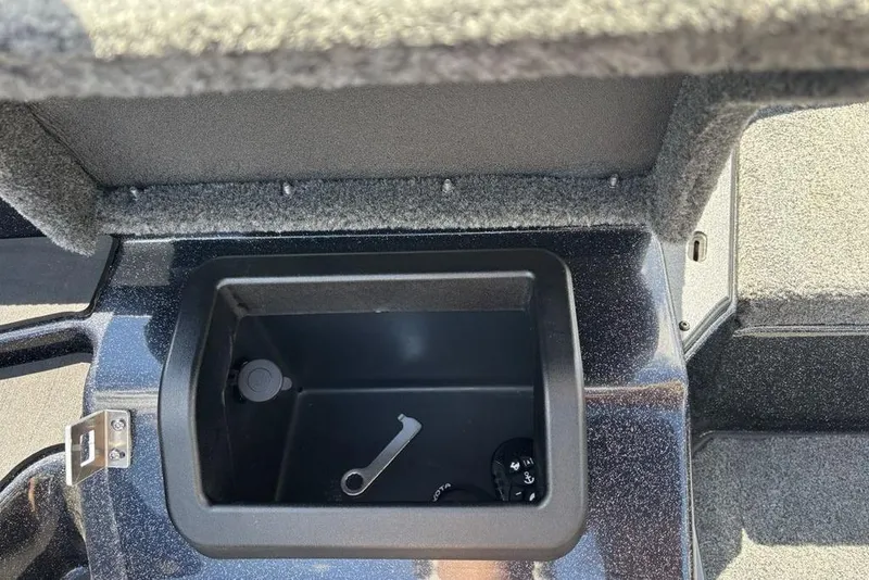 Slide: The Image of Storage compartment in a 2026 Skeeter ZXE20 boat, featuring a wrench and key. - 37
