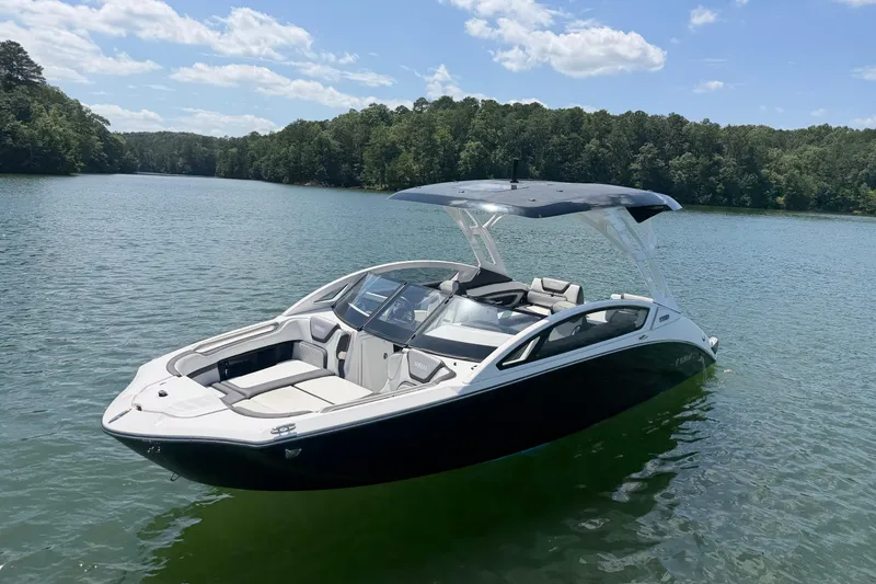 Slide: The Image of 2021 Yamaha Boats 275SD on a serene lake with lush forest backdrop. - 2