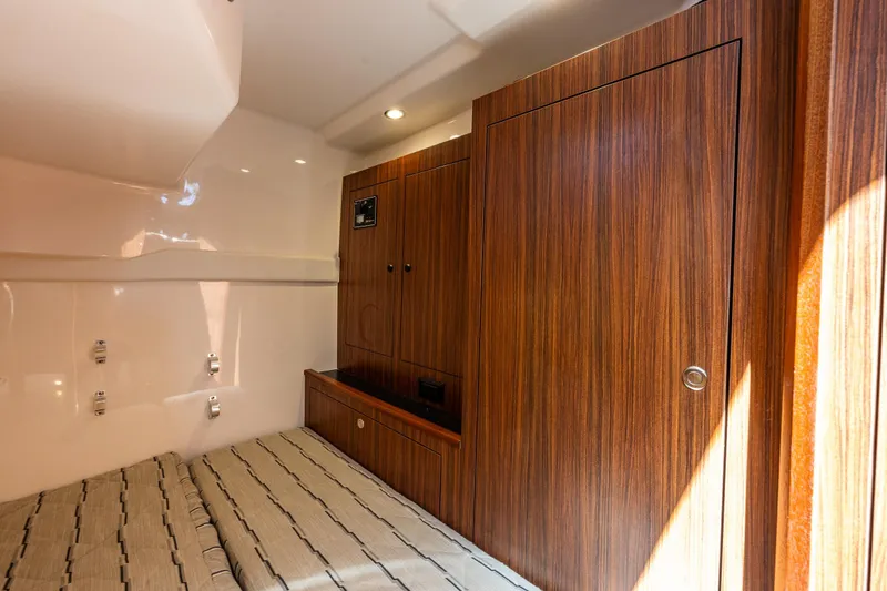 Slide: The Image of 2021 Pursuit OS 355 Offshore cabin interior with wood paneling and bed. - 15