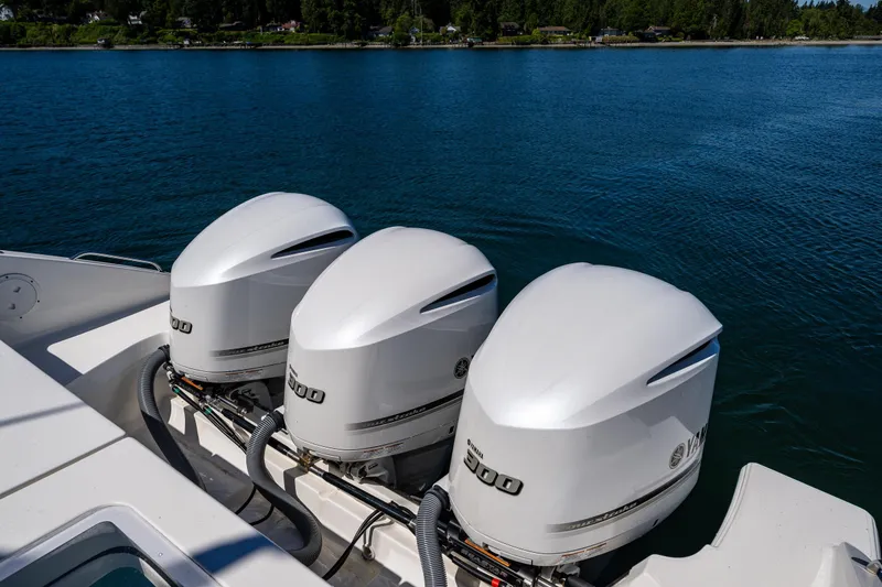 Slide: The Image of Triple Yamaha outboard engines on a 2021 Pursuit OS 355 Offshore boat, cruising on a serene lake. - 22