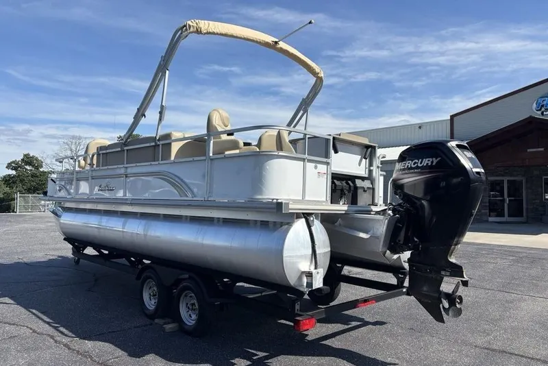 Slide: The Image of 2016 SunChaser 8525 pontoon boat with Mercury outboard motor on trailer, parked outdoors. - 2