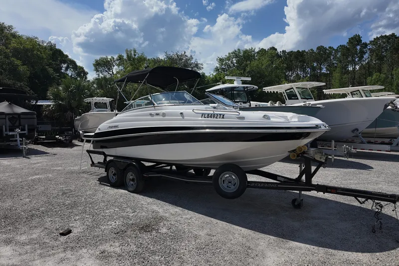 The Image of 2009 Four Winns F224 boat on trailer, parked outdoors under a cloudy sky. - 0