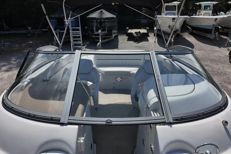 Slide: The Image of 2009 Four Winns F224 boat interior with seating, windshield, and canopy in a marina setting. - 14