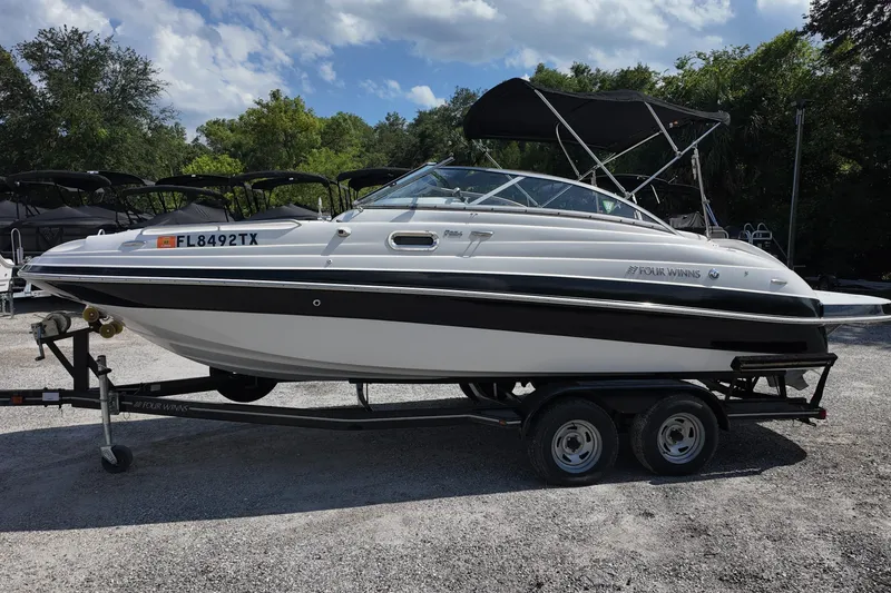 Slide: The Image of 2009 Four Winns F224 boat on trailer, parked outdoors under a cloudy sky. - 2
