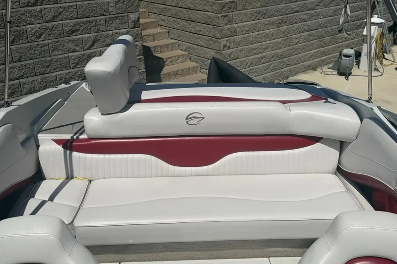 Slide: The Image of 2013 Crownline 21 SS boat interior with white and red seating, docked near a stone wall. - 6