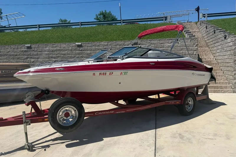 The Image of 2013 Crownline 21 SS boat on trailer, red and white design, parked outdoors. - 0