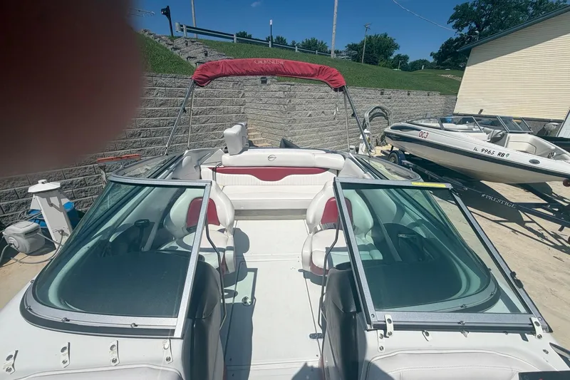 Slide: The Image of 2013 Crownline 21 SS boat with red canopy and white interior, docked outdoors. - 11