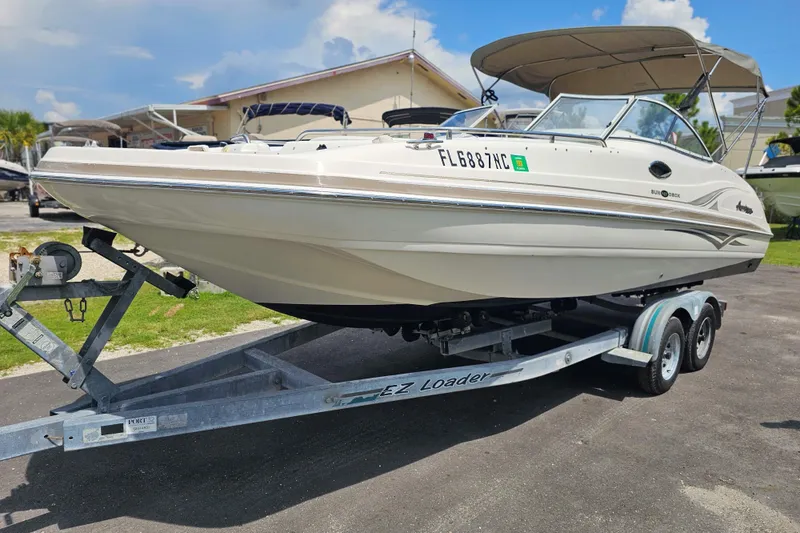 The Image of 2006 Hurricane SunDeck 237 DC OB boat on trailer, parked outdoors under a clear sky. - 0