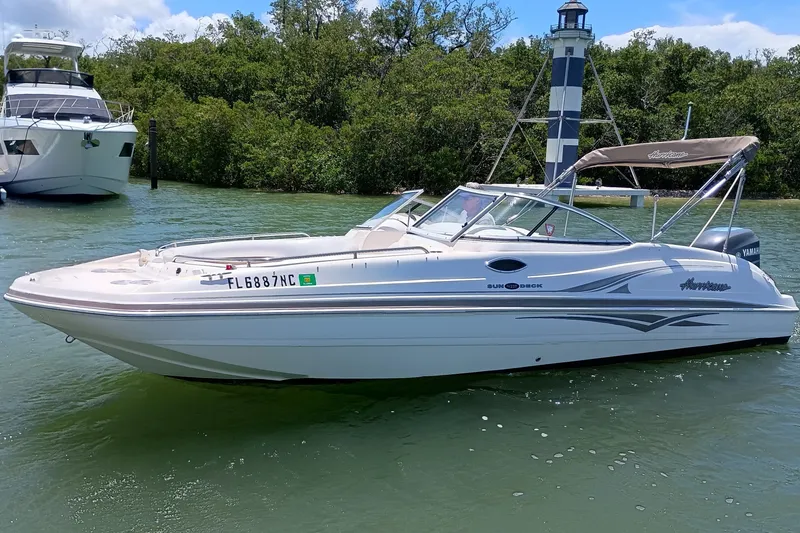 The Image of 2006 Hurricane SunDeck 237 DC OB boat on water near lighthouse and trees. - 0