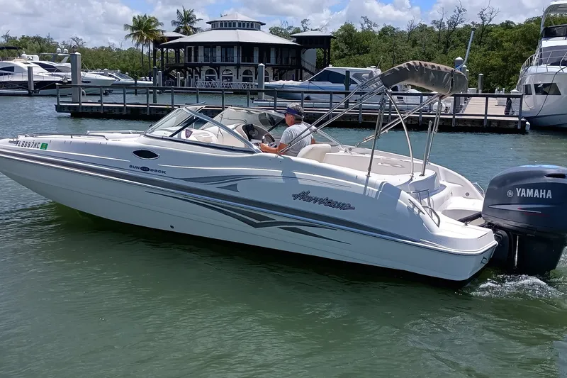Slide: The Image of 2006 Hurricane SunDeck 237 DC OB boat cruising near a marina with Yamaha outboard motor. - 1